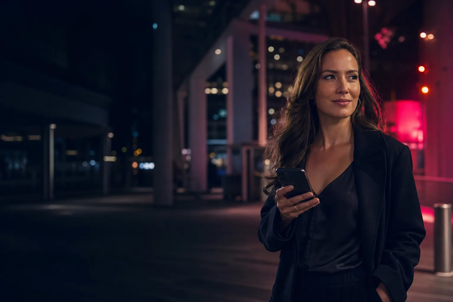 Adult woman using her phone confidently in a city plaza at night